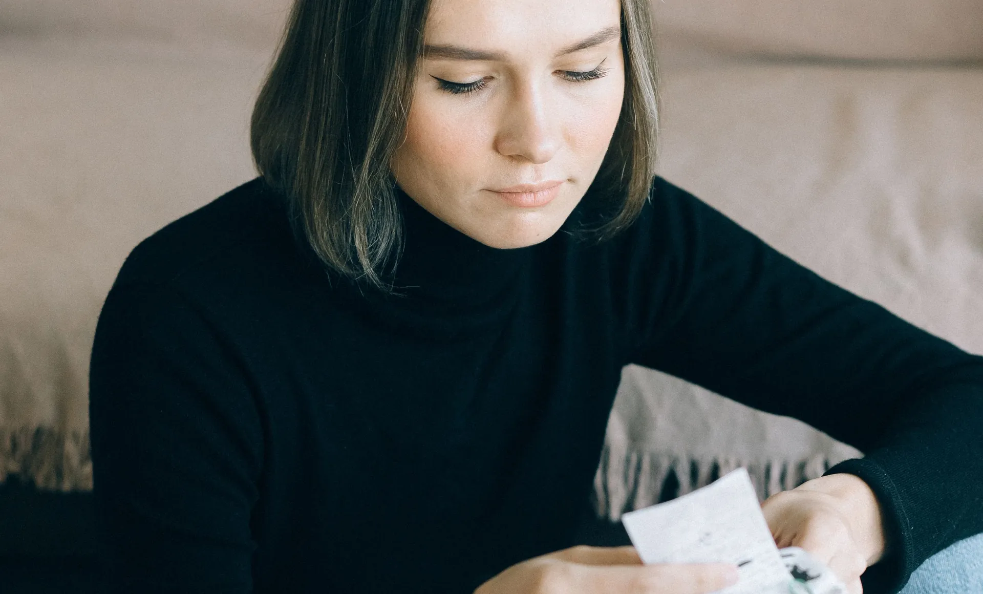 Una persona revisa boletas y usa una calculadora sobre la mesa de su casa.
